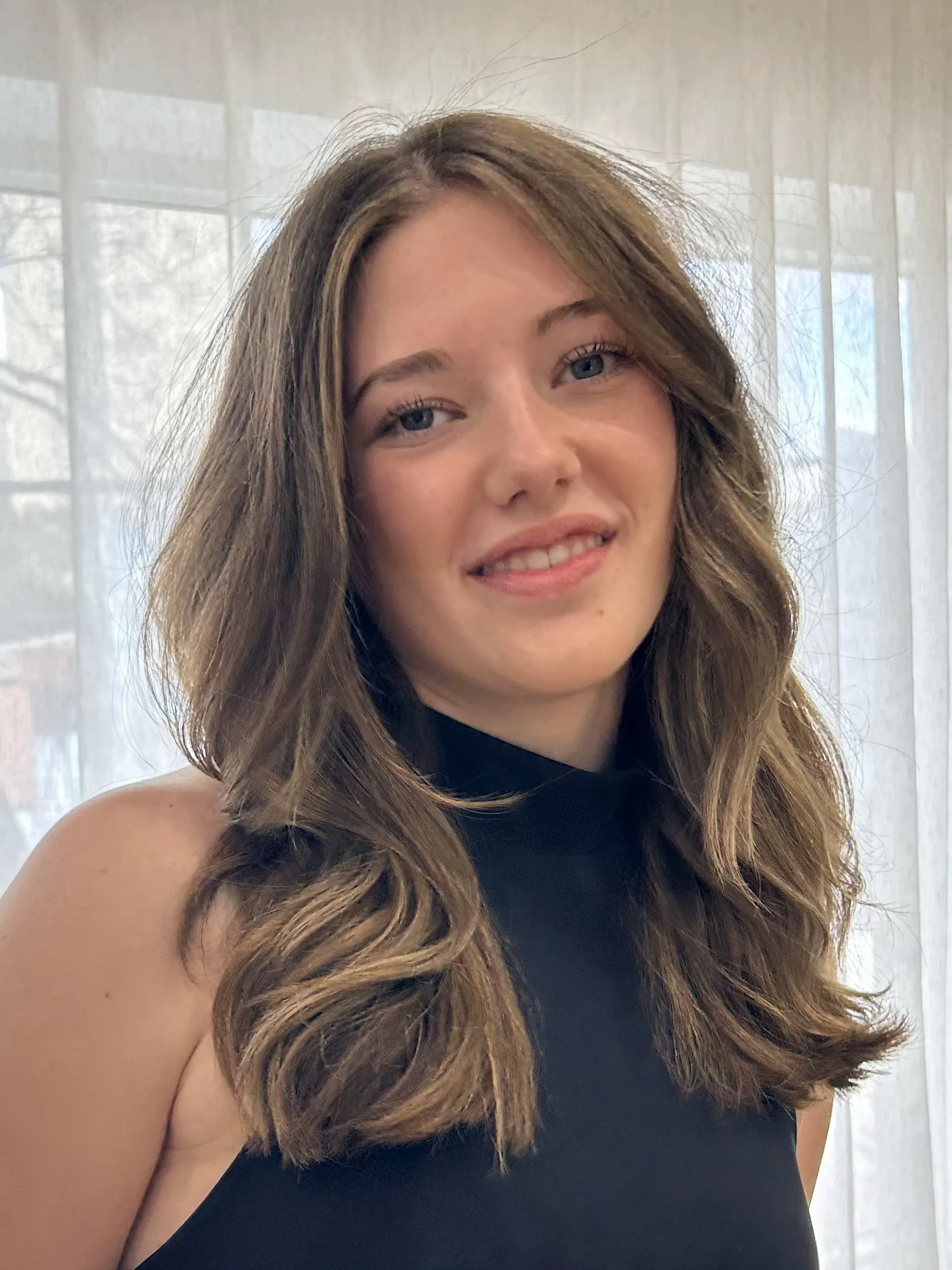 Seated client smiling, mid-length bronde blowout