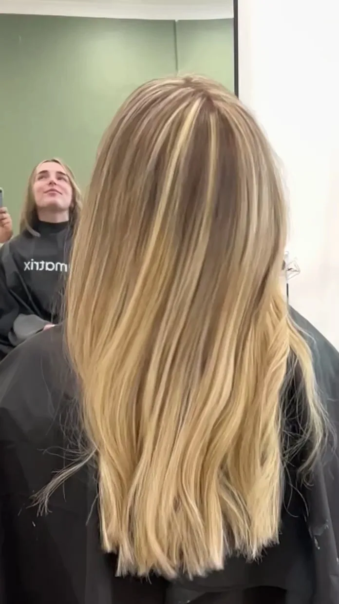 Long warm-blonde hair against a black cape